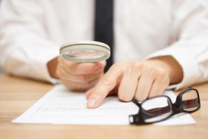 Focused businessman is reading through  magnifying glass document